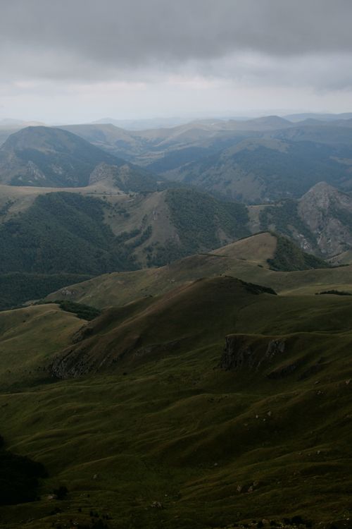 Free Scenic view of rolling hills and mountains under cloudy sky, ideal for nature travel. Stock Photo