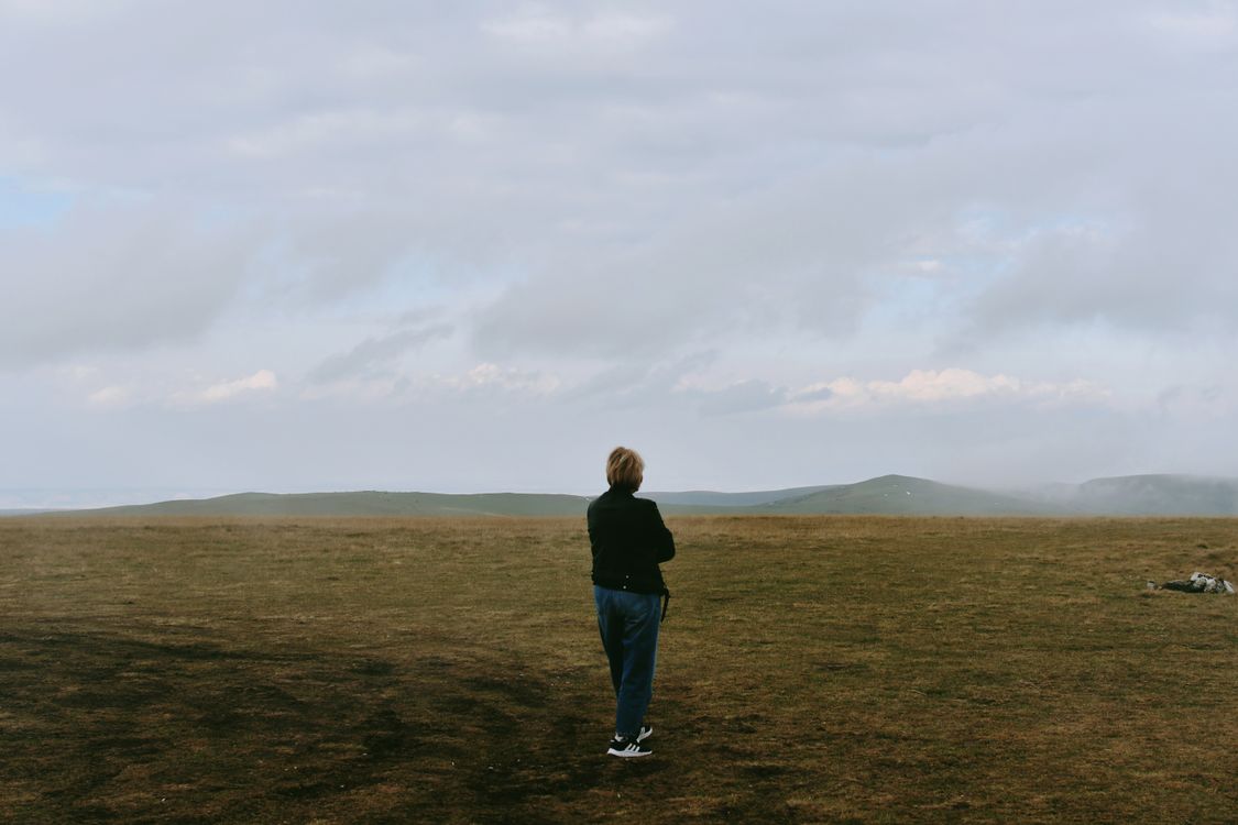 A person standing in a field looking at the sky · Free Stock Photo