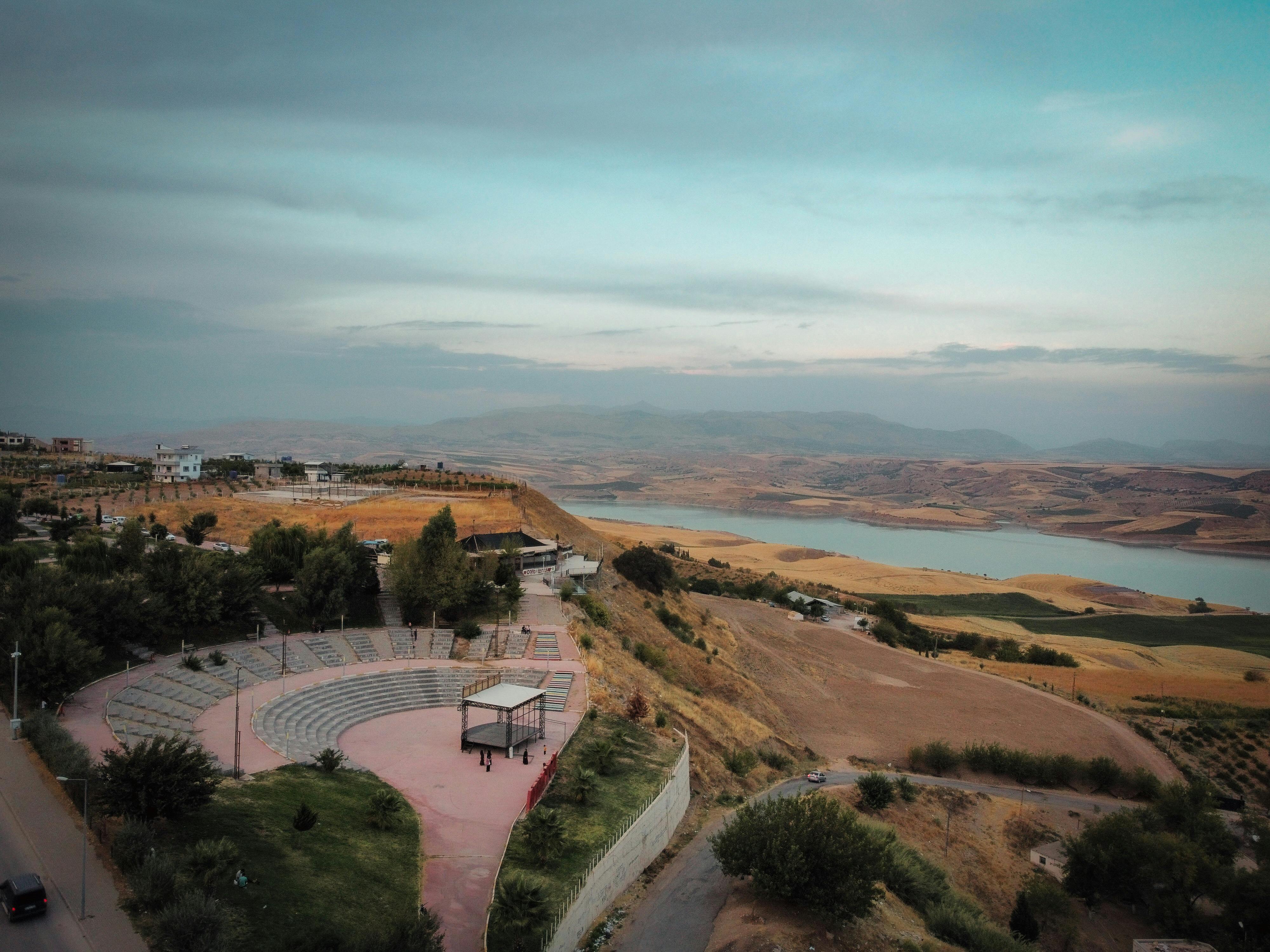 Free Drone shot of a scenic valley with an amphitheater and river, showcasing rural beauty. Stock Photo
