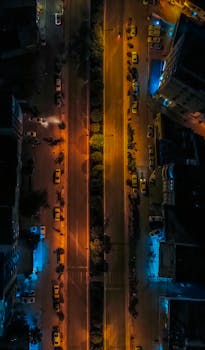 A mesmerizing top view shot of a city street illuminated at night, highlighting vibrant city lights.