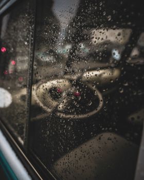 Close-up of raindrops on a car window capturing a blurred reflection of the cityscape.