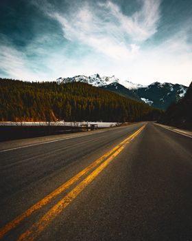 Empty highway leading through snow-capped mountains in Whistler, Canada, during fall.
