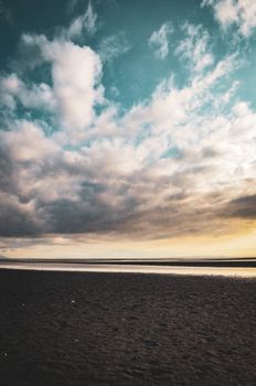 A captivating beachscape showcasing dramatic storm clouds over a serene shoreline at sunset.