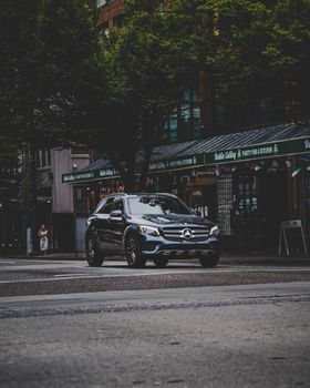 A Mercedes car drives through a rainy urban street, showcasing modern city life.