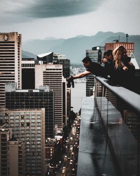 Dramatic cityscape view of downtown skyscrapers at sunset with people overlooking the urban skyline.