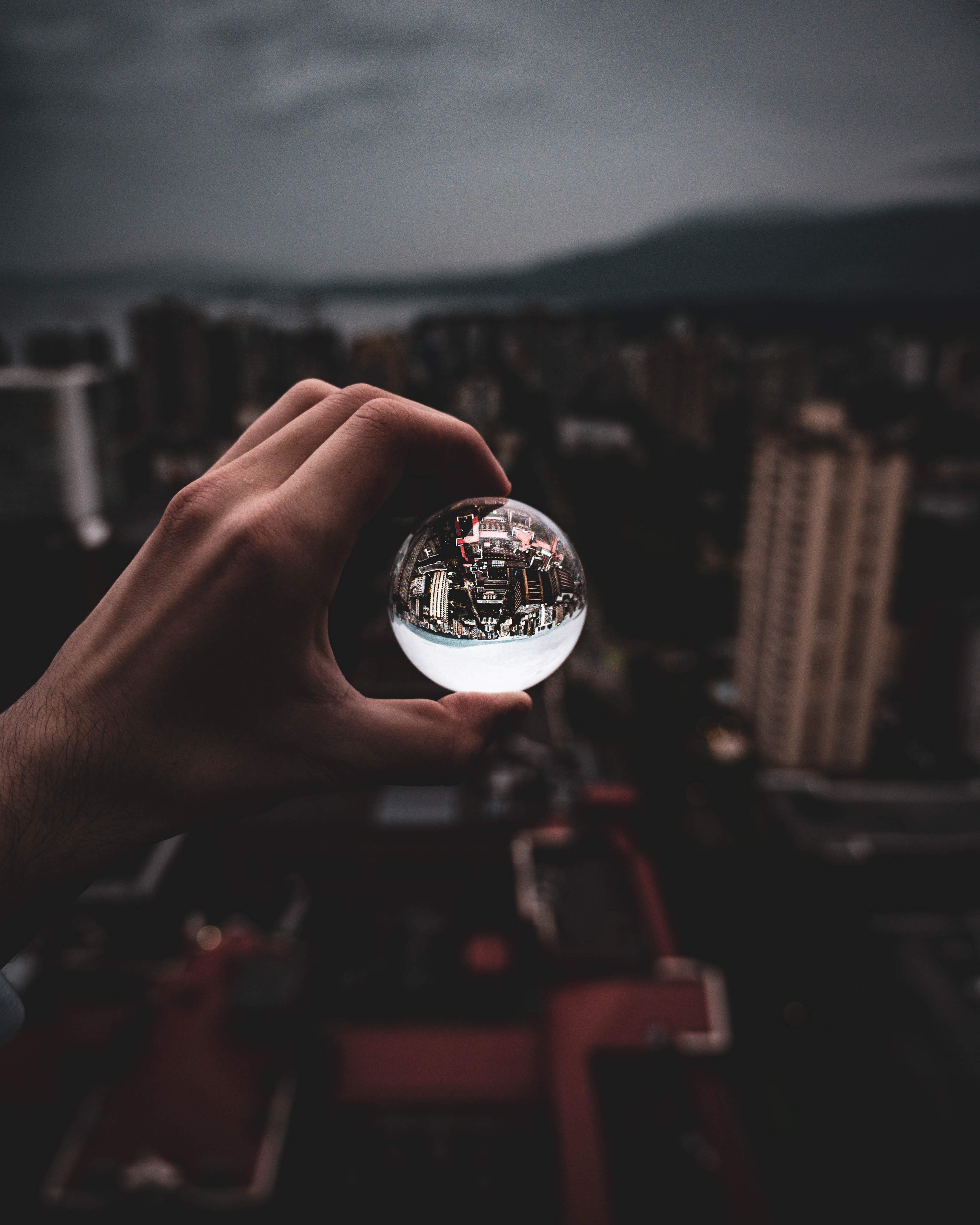 A person holding a glass ball in front of a city · Free Stock Photo