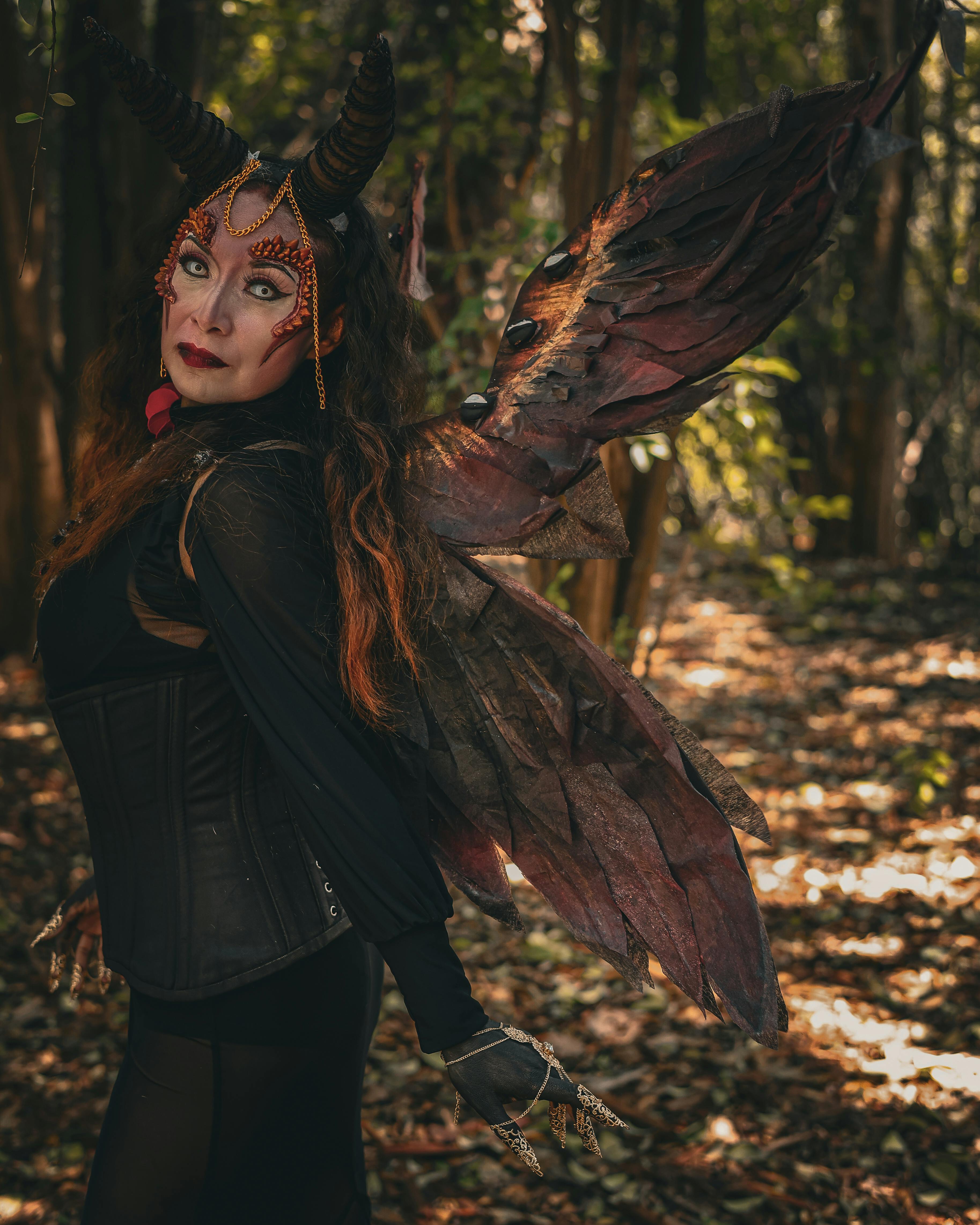 woman dressed as a demon with wings in the forest