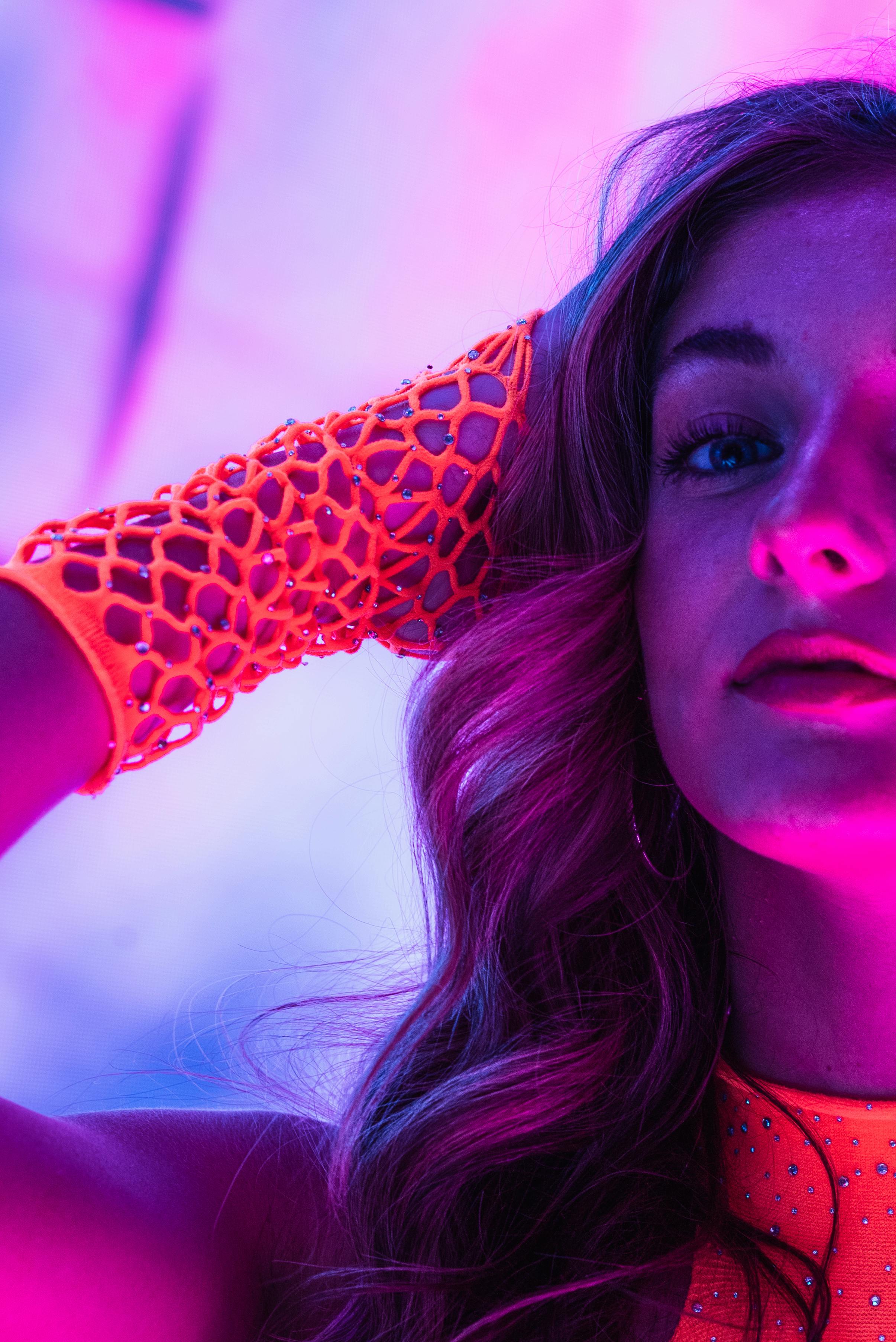 Captivating portrait of a woman in neon light, featuring vibrant colors and trendy fashion.