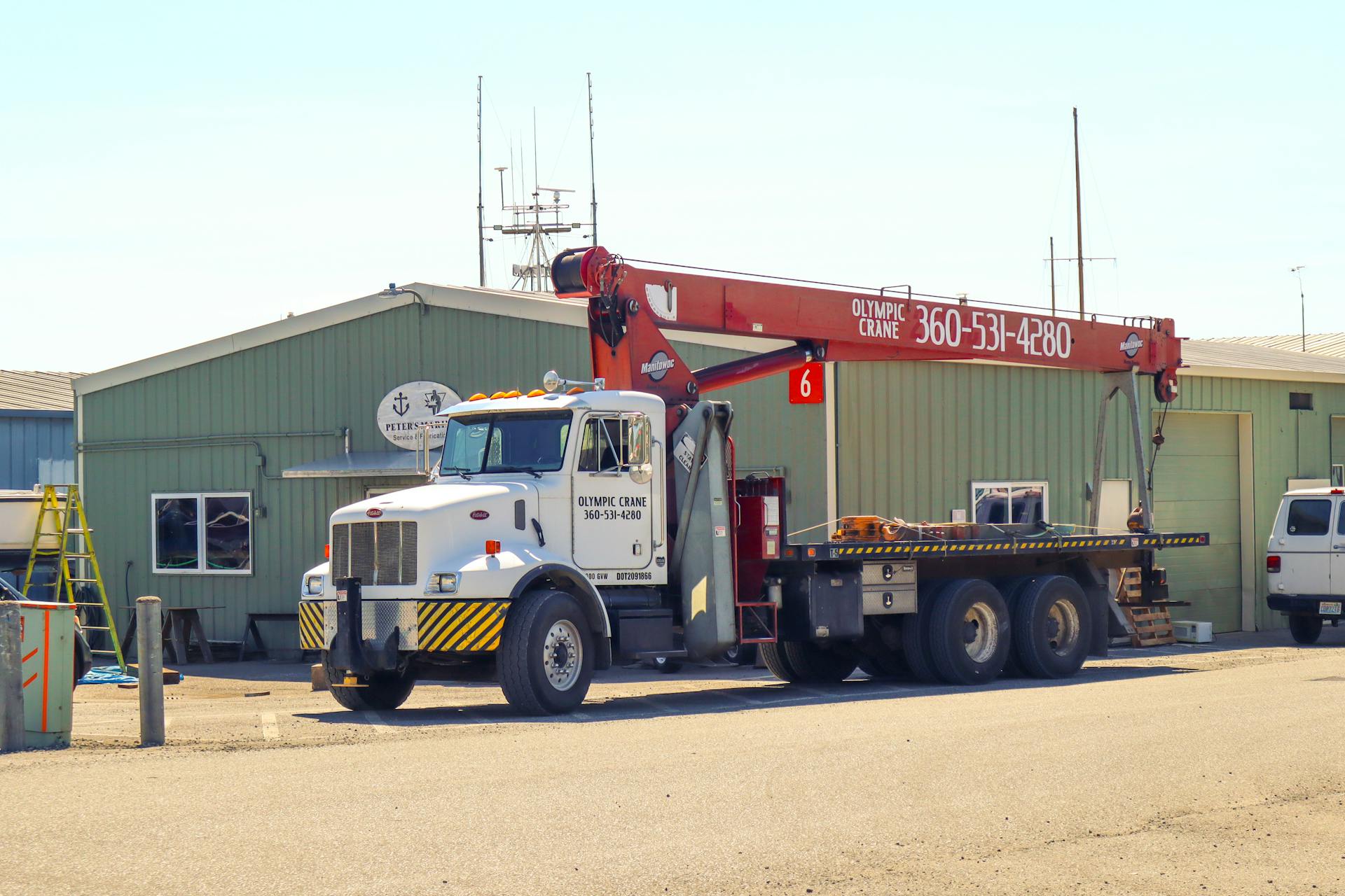 Crane truck parked outside a warehouse in Port Townsend, WA, on a sunny day.