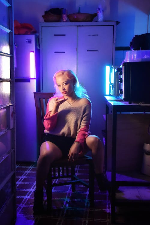 A woman sitting in a chair with neon lights