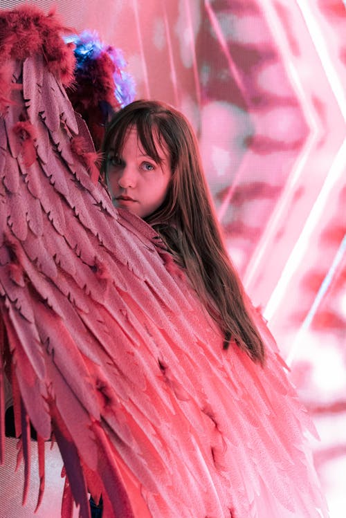 A girl with long hair and wings holding a pink feather