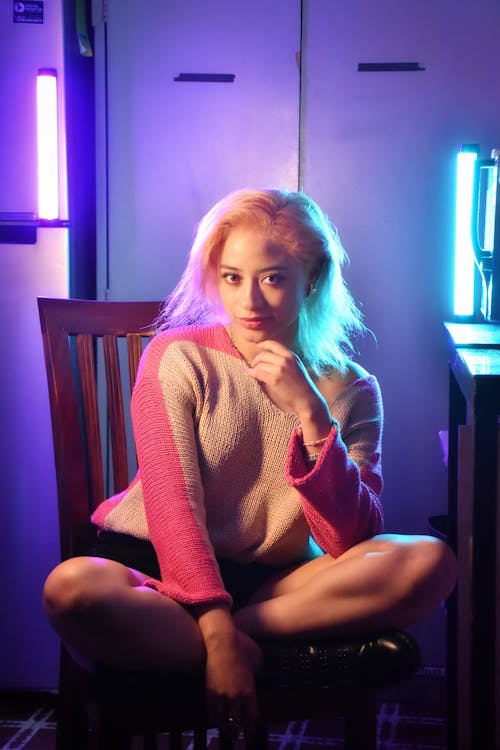 A woman sitting on a chair in front of neon lights
