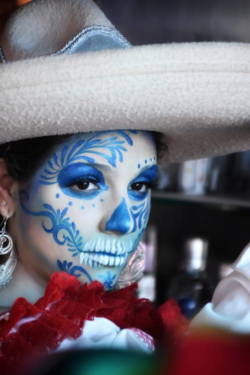 A woman with blue and white face paint and a hat