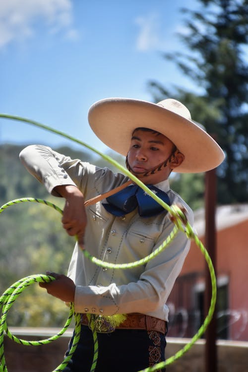A man in a cowboy hat is holding a lasso