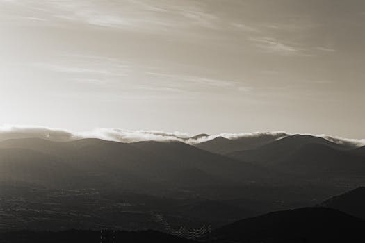 Breathtaking view of mountain range with rolling clouds under a soft sky.
