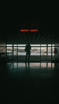 A lone figure stands silhouetted at the Eminönü-Kadıköy ferry terminal.