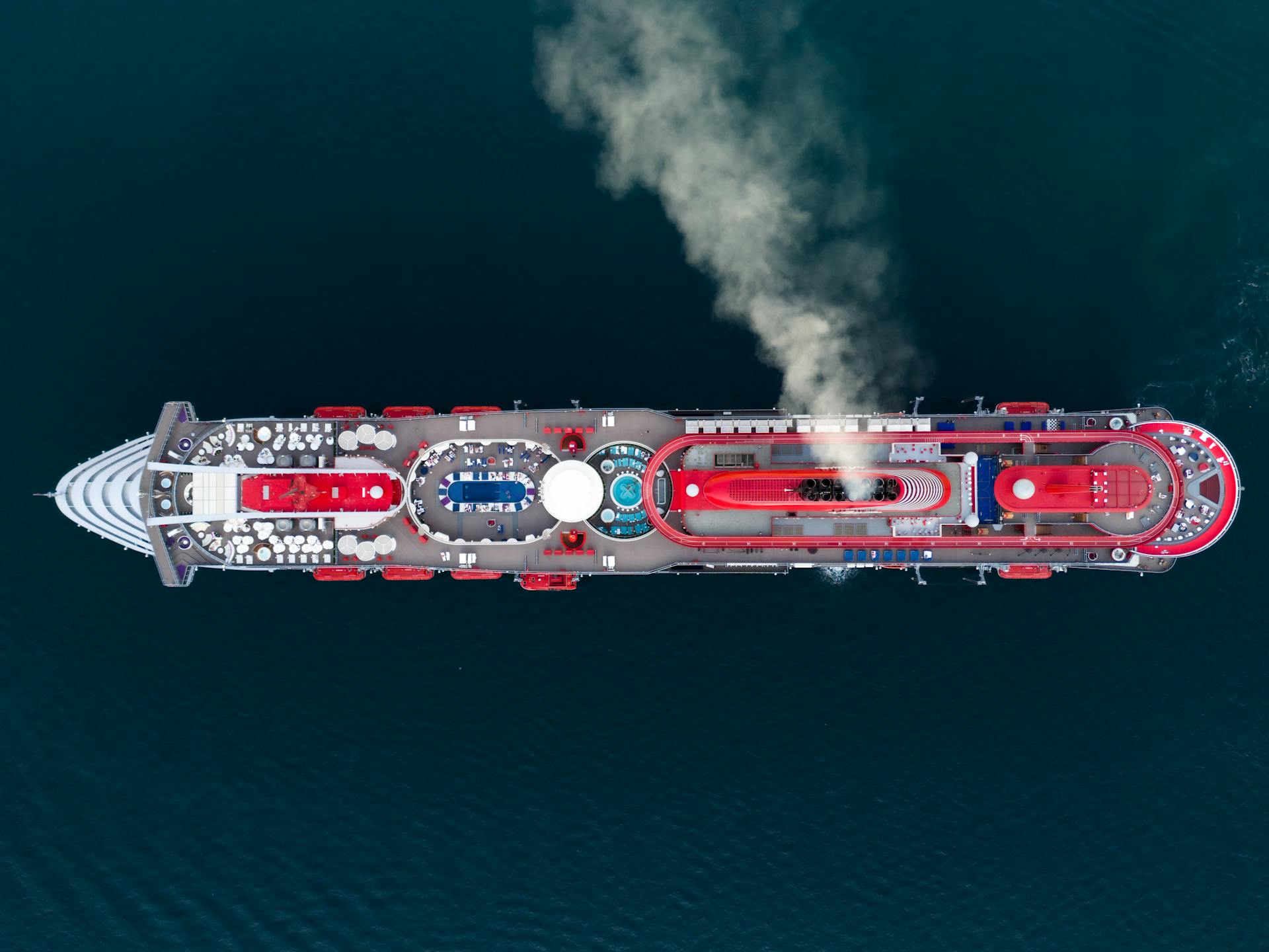 Drone shot of a cruise ship sailing in Kotor Bay, Montenegro, showcasing vibrant deck details.