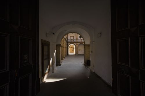 Free Explore the serene beauty of a historic courtyard corridor in Jičín, Česko, captured in dramatic light and shadow. Stock Photo