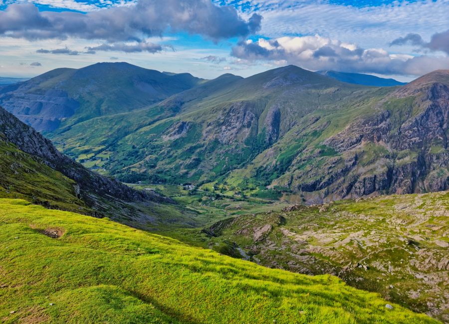 Breathtaking view of rugged mountains and green valleys under a vibrant blue sky.
