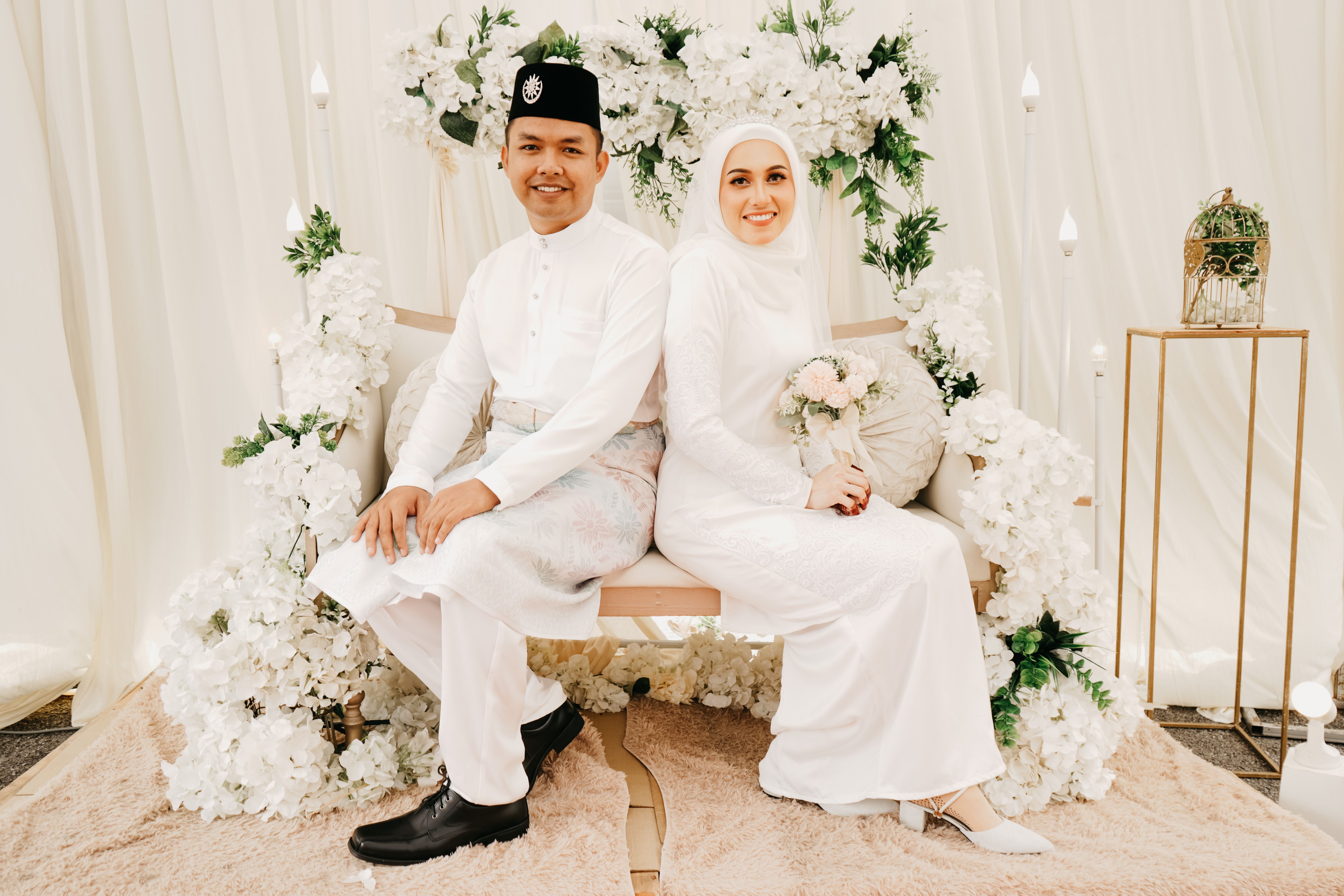Beautiful wedding portrait featuring a smiling newlywed couple in traditional attire with floral decor.