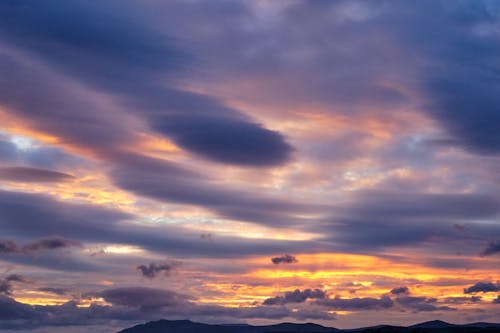 A sunset over the ocean with clouds and mountains