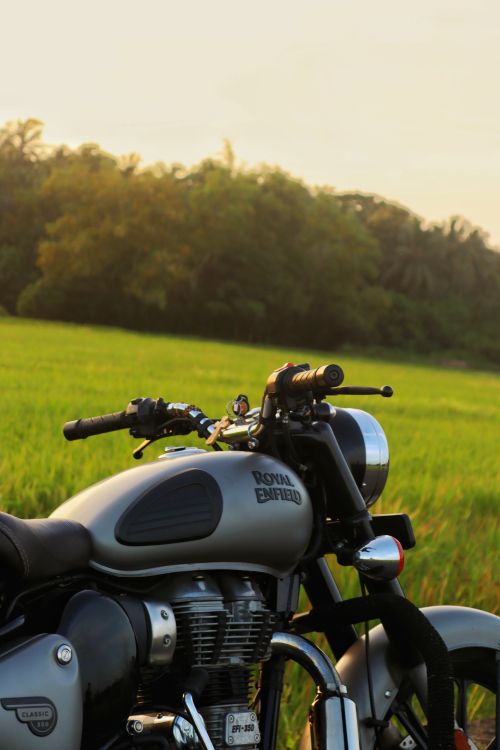 Free Motorbike parked in lush green countryside, capturing a tranquil sunset scene. Stock Photo