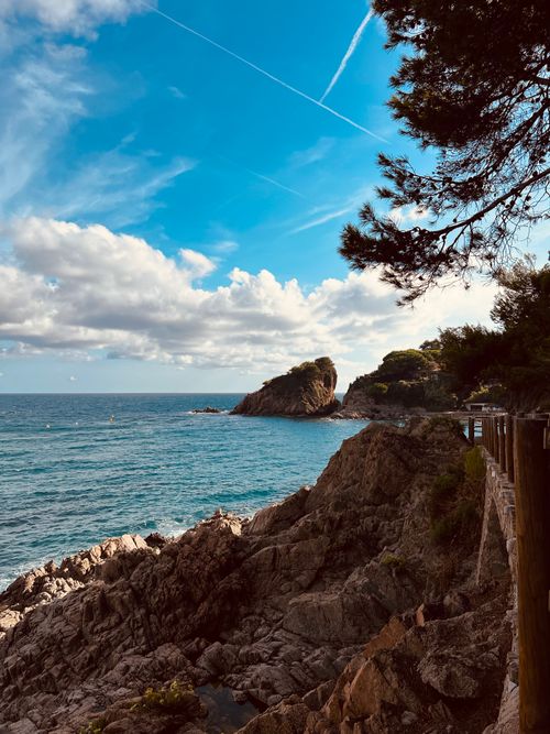 Free Beautiful coastal view with rocky cliffs and clear blue ocean under a vibrant sky. Stock Photo