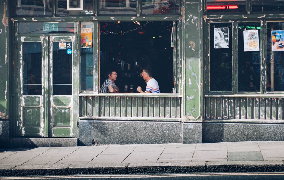 Two men enjoy a casual conversation inside a vintage-style café.