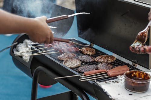 Persona Che Griglia Salsiccia E Carne