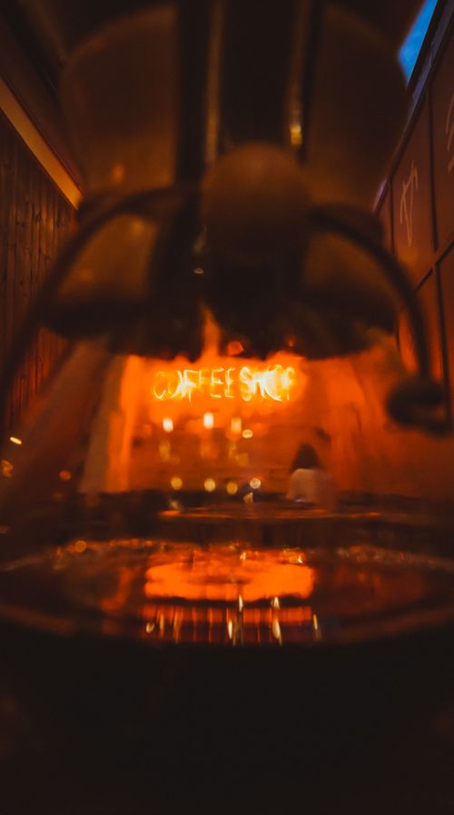 Free Cozy café interior featuring a glowing 'Coffee Shop' neon sign enhancing the ambiance. Stock Photo