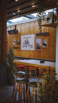 Cozy bar interior showcasing wooden furniture and decor, accented with green plants.