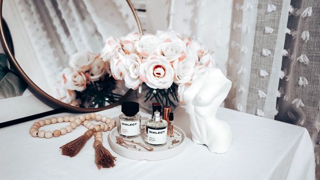 Chic vanity display featuring a bouquet, perfume bottles, and jewelry with a mirror backdrop. Perfect for home decor.