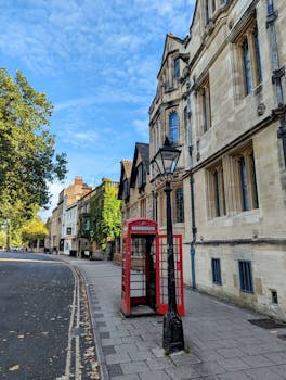 Classic street scene in Oxford, England featuring a vintage red telephone booth and historic architecture.