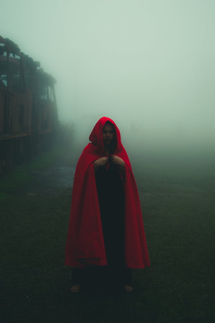 Woman In Red Cloak Walking Through Mist