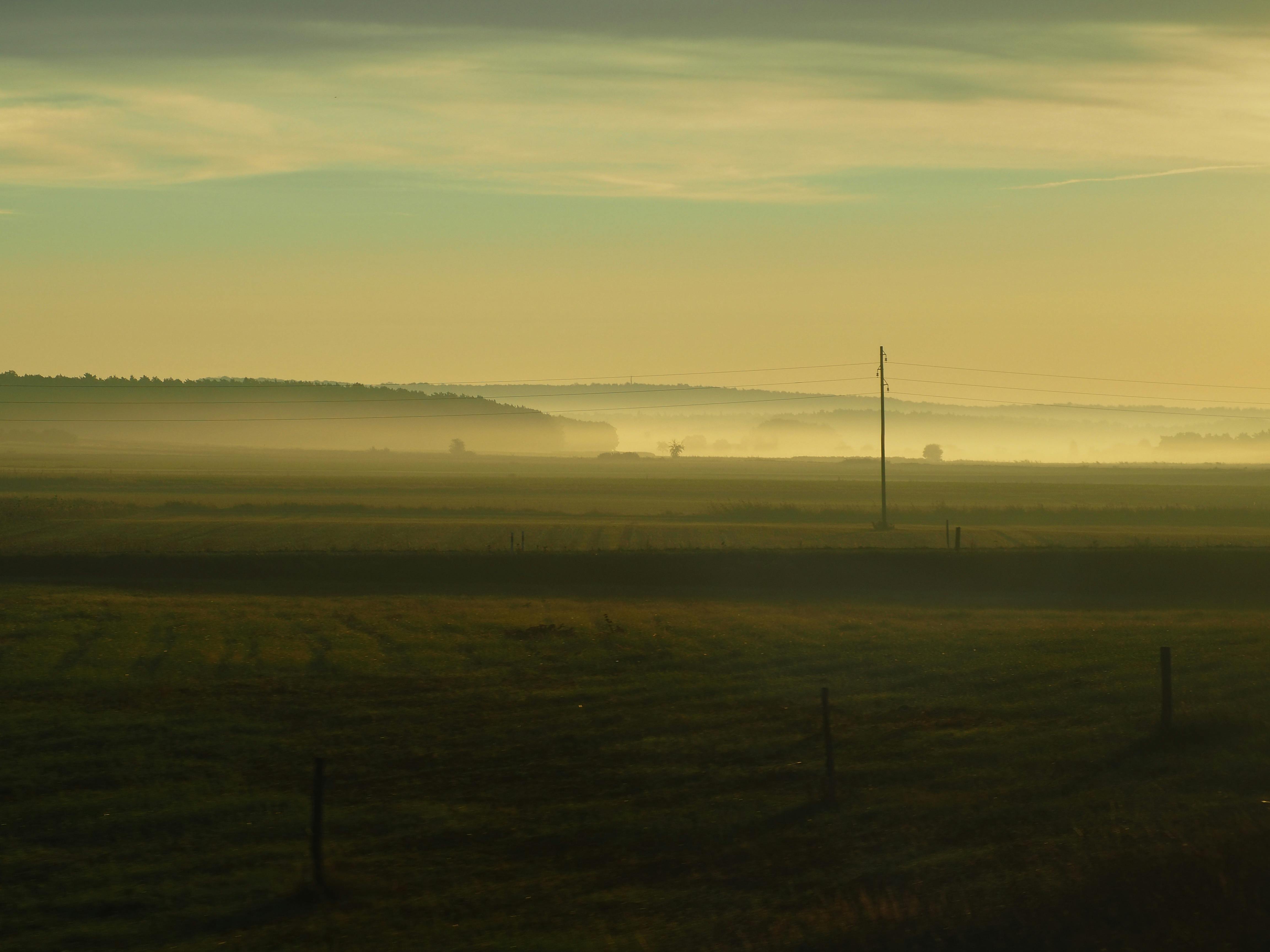 Tranquil countryside view with misty fields at sunrise, capturing the serene ambiance of nature.