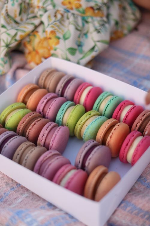 Free Colorful macarons in a box on a patterned picnic blanket. Perfect for food lovers. Stock Photo