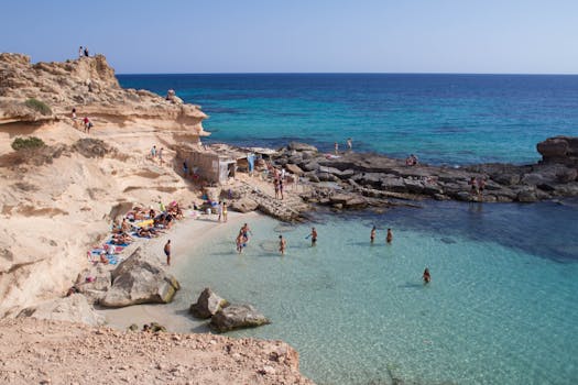 Stunning coastline photo capturing beachgoers at a rocky cove in Illes Balears, Spain.