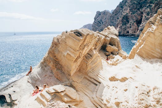 Explore the stunning cliffside views and sunbathers on a beautiful beach in San Juan Bautista, Spain.