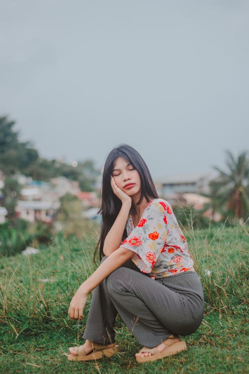 Woman Squatting and Posing with Hand on Cheek