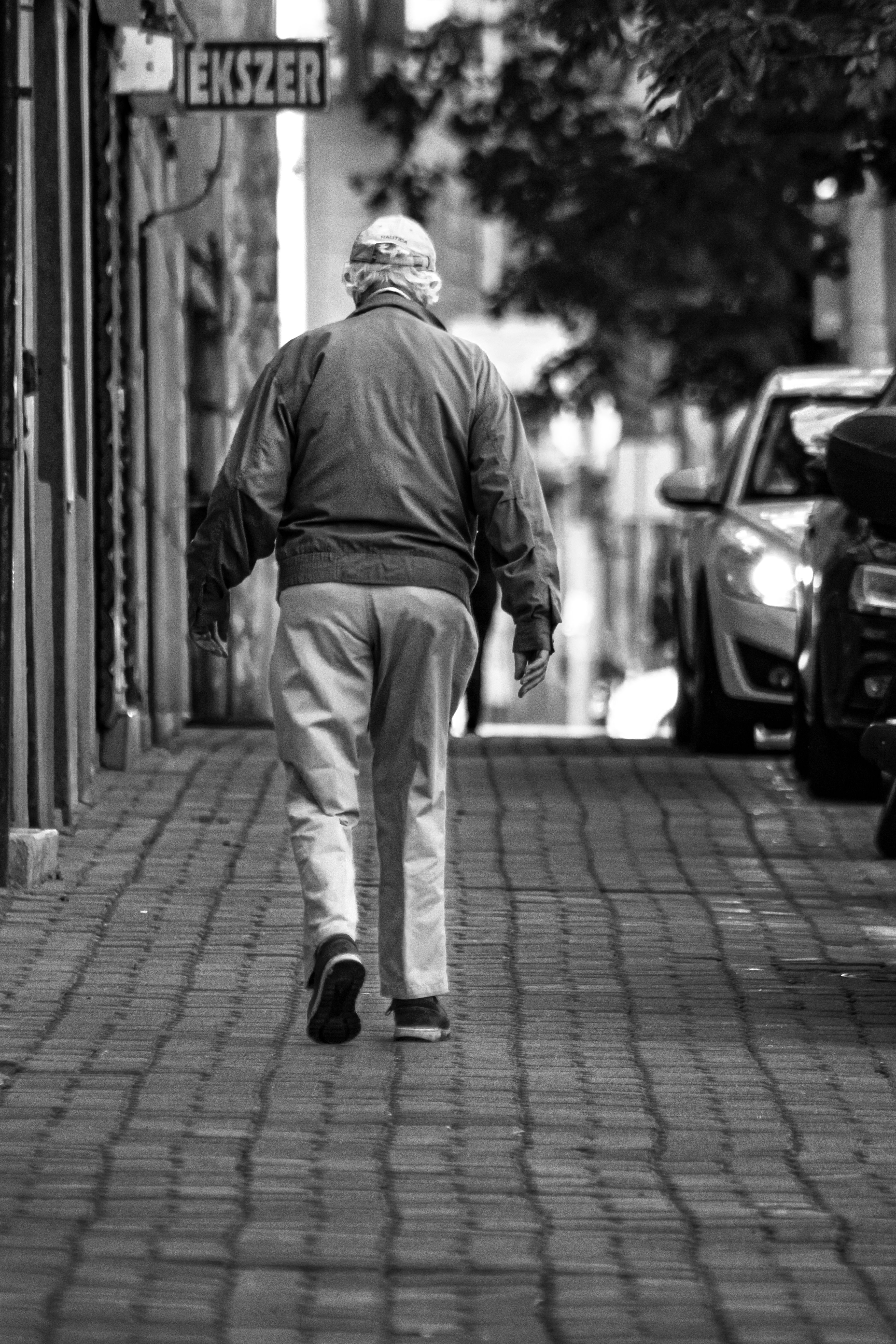 Black and white image of man walking on a city sidewalk.