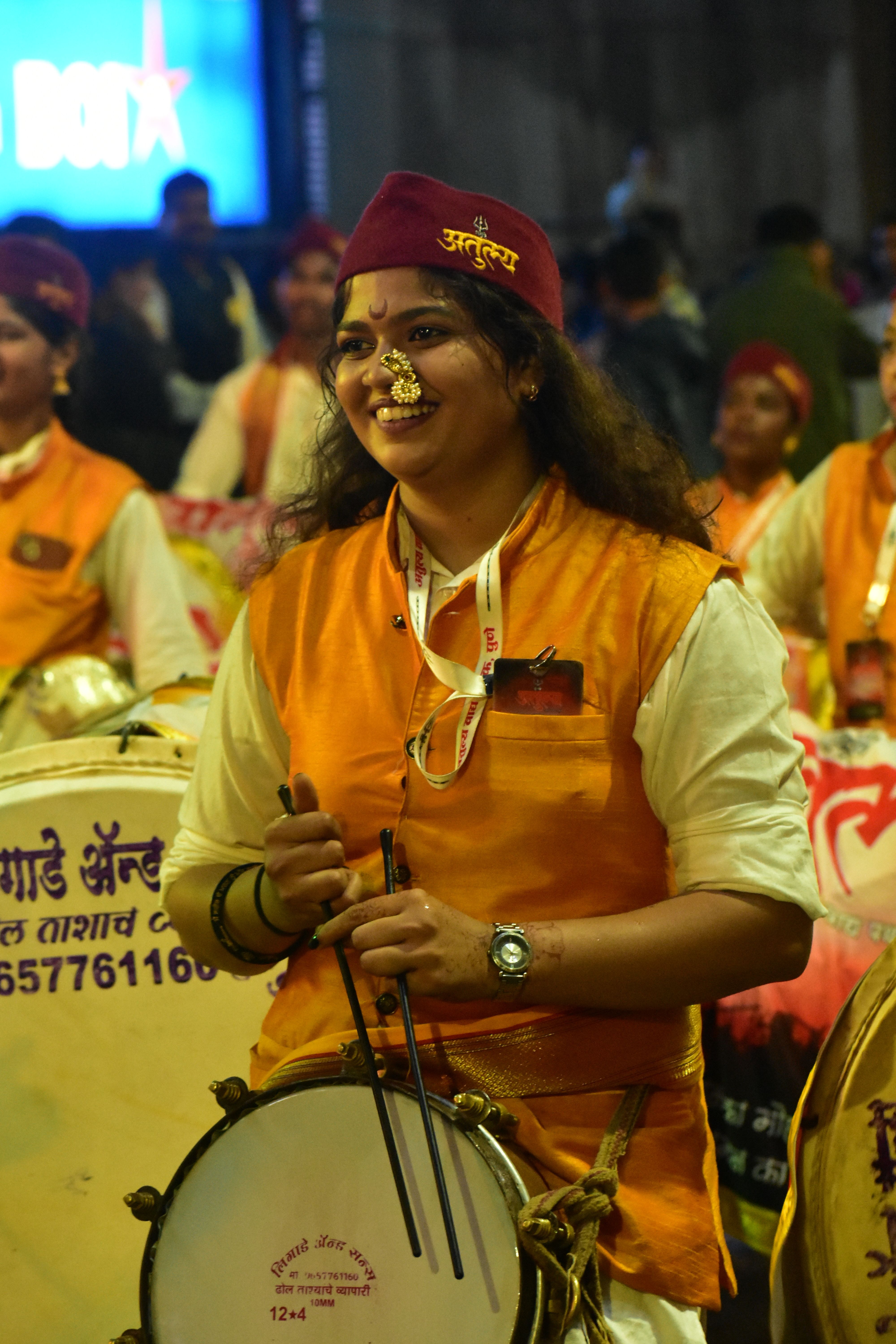 Joyful woman drummer in traditional attire performing at night festival.