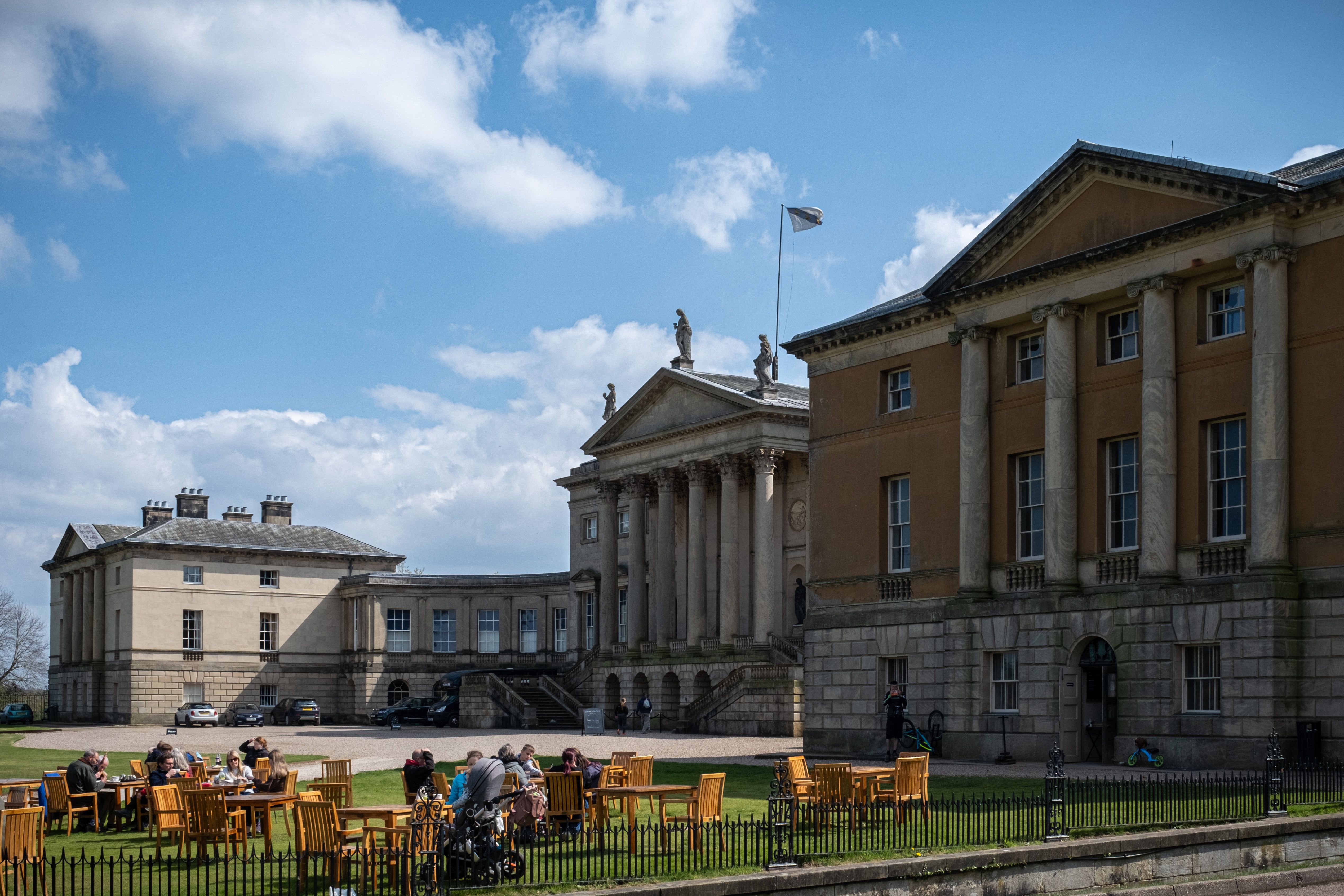 Beautiful view of the historic Kendalston Hall with tourists enjoying the outdoor atmosphere.