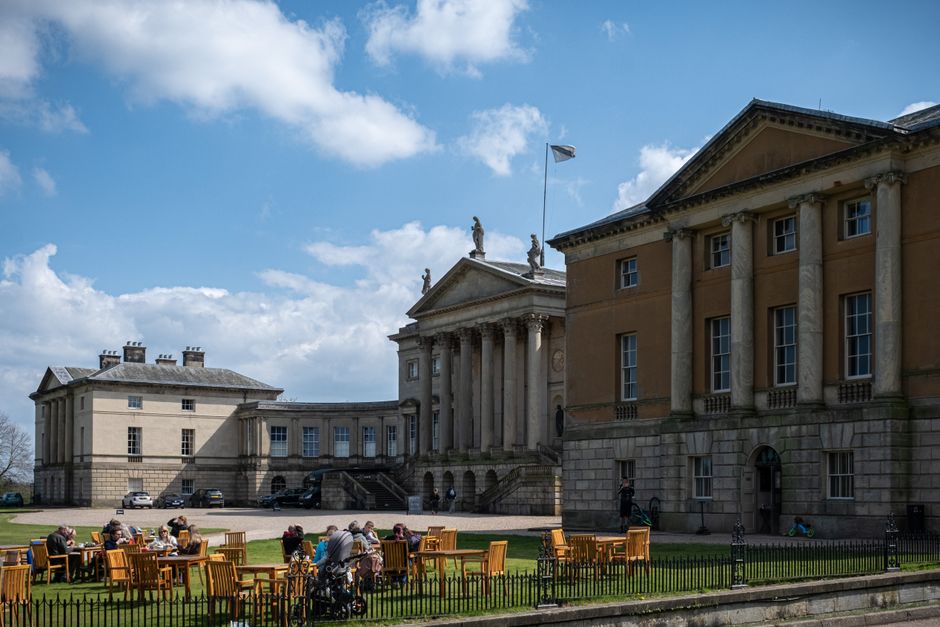 Beautiful view of the historic Kendalston Hall with tourists enjoying the outdoor atmosphere.