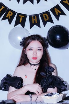 Elegant woman in black outfit at a birthday party with festive decorations.