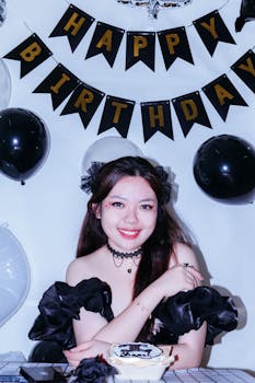 Young woman celebrating birthday with balloons, cake, and decor.