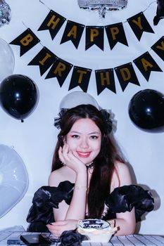 Elegant portrait of a woman celebrating a birthday with decor and cake.
