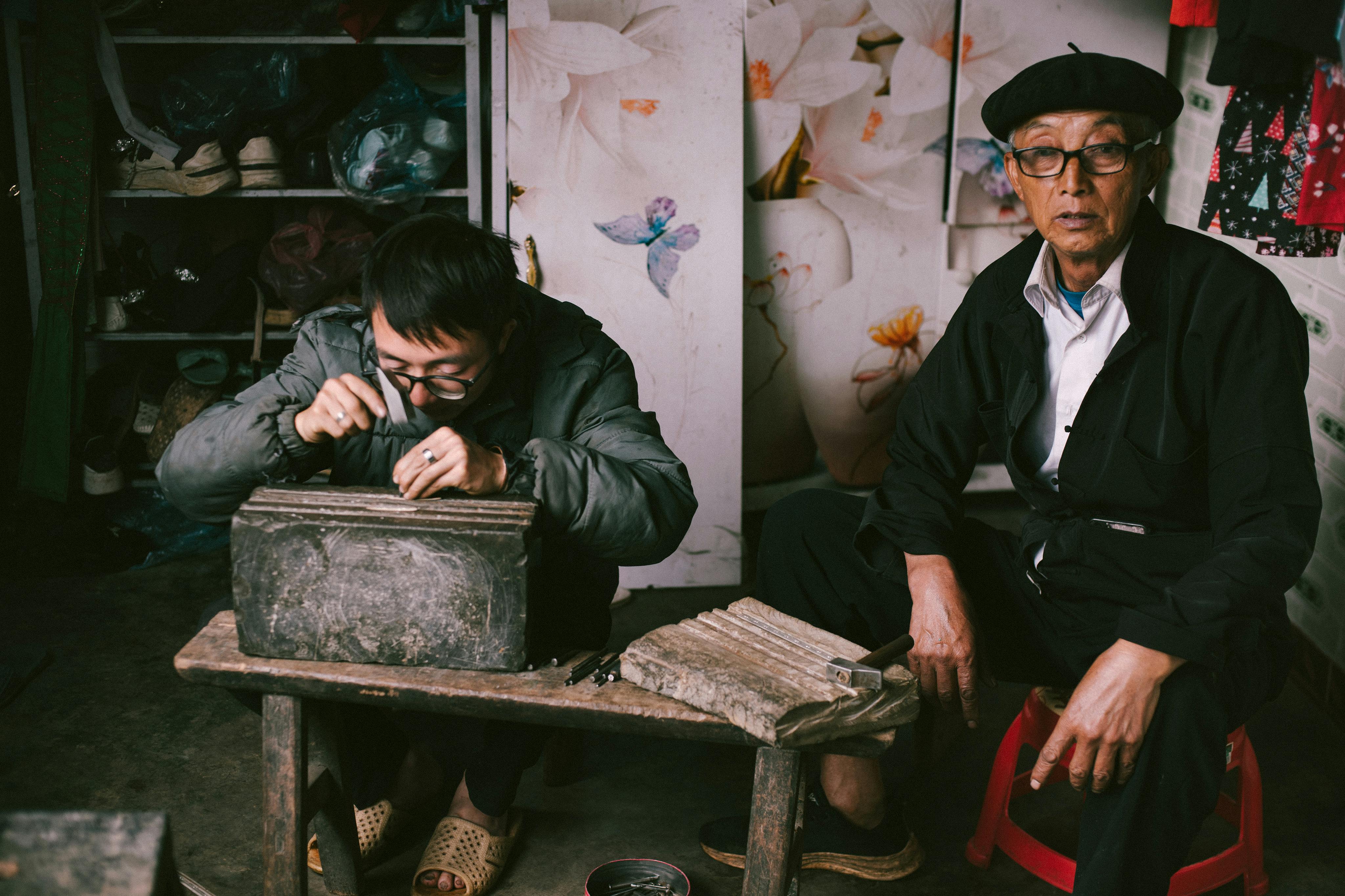 Two men crafting with tools in a cozy workshop setting.