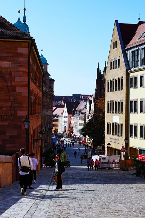 Free Charming cobbled street in a historic European city with pedestrians and classic architecture. Stock Photo