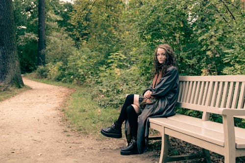 Woman Sitting on Wooden Bench in a Forest 