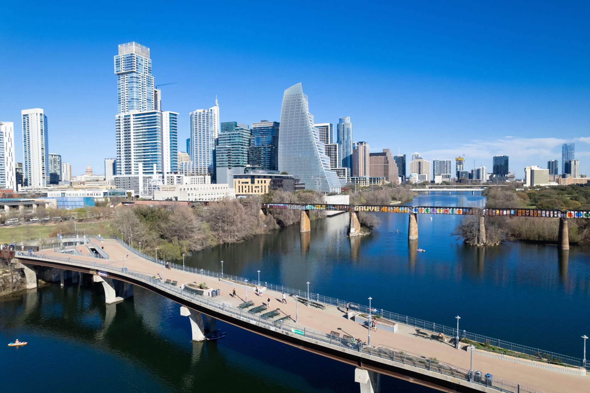 Kayakers on Lady Bird Lake facing Austin skyline, golden-hour light and lively riverside trails